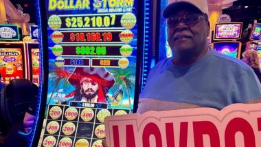 Man holding jackpot sign in front of gaming machine