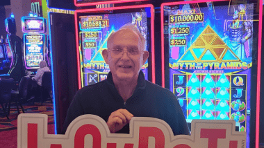 Man holding jackpot sign in front of gaming machine. 