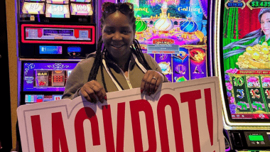 Woman holding jackpot sign in front of gaming machine.