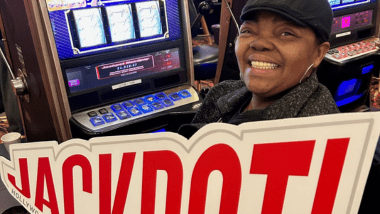 Woman holding jackpot sign near gaming machine.