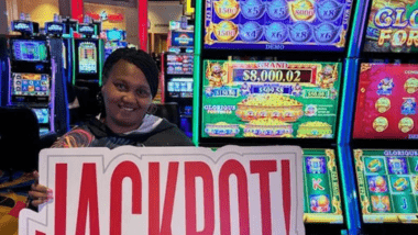 Woman holding Jackpot sign in front of gaming machine.