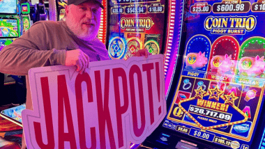 Man holding jackpot sign near gaming machine. 