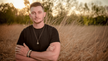 Man with arms crossed standing in field.