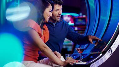 Man and woman sitting at vlt playing the machine.