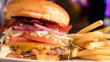 bacon cheeseburger with tomato onion and lettuce and fries on a plate